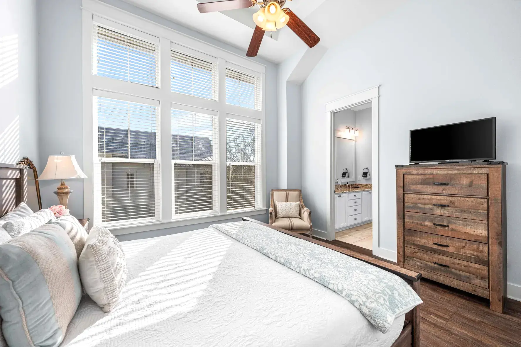 Vaulted guest bedroom with chest of drawers, TV, and view to the ensuite bath