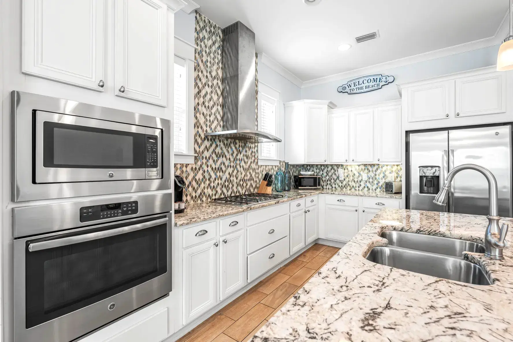 Premium GE wall oven, microwave, and gas cooktop on a granite-topped run of cabinets